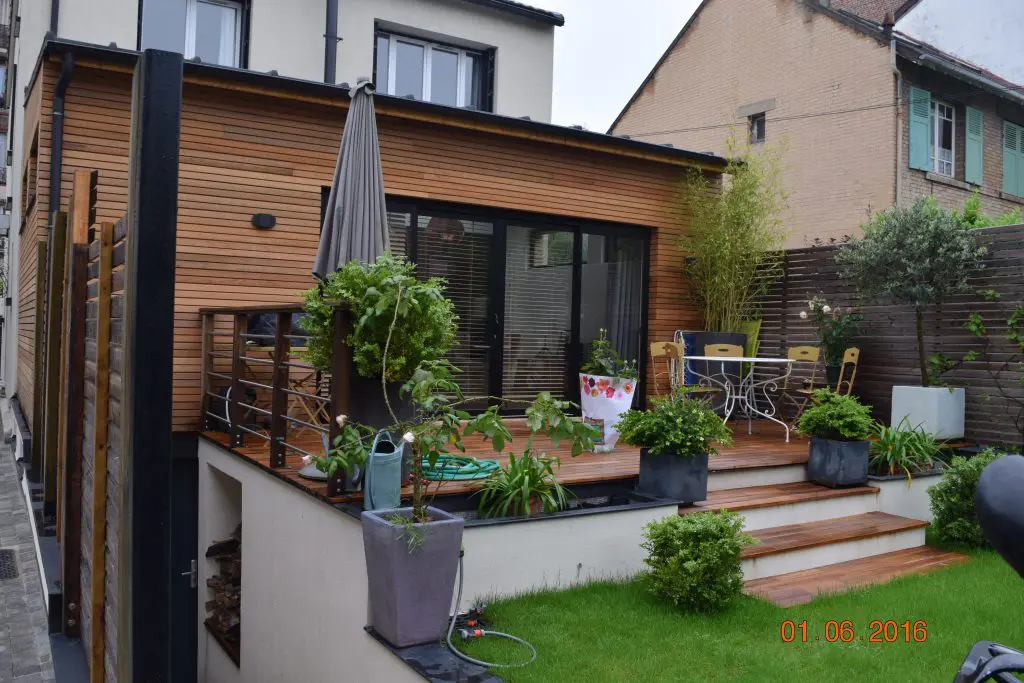 Terrasse en parquet extérieur avec petite table d'extérieur et espace vert